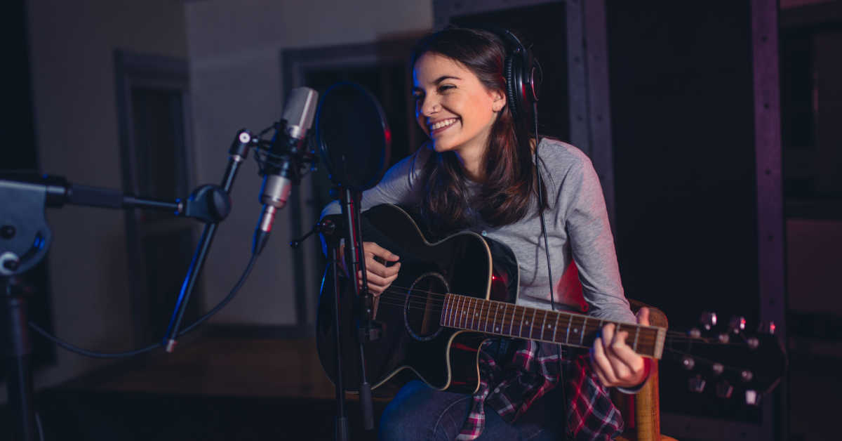 female singer playing guitar and singing a song for a spotify studio recording
