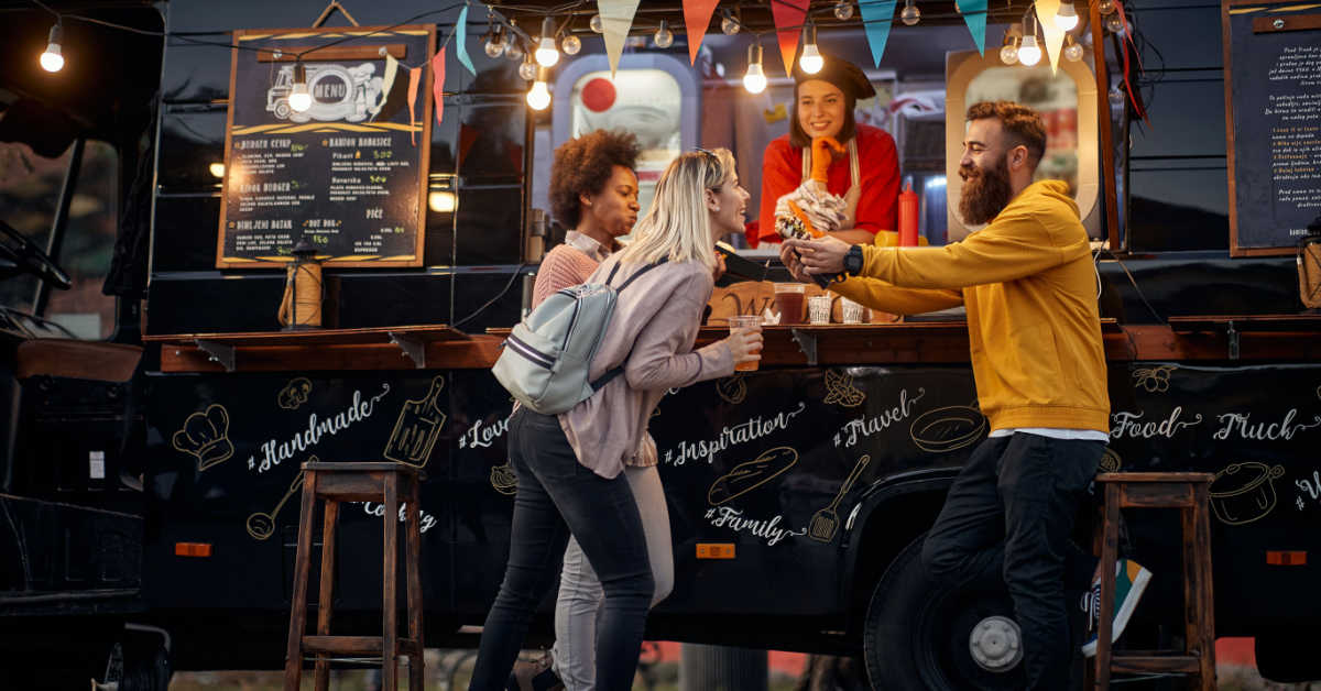 group of young people having fun while eating at small business food truck